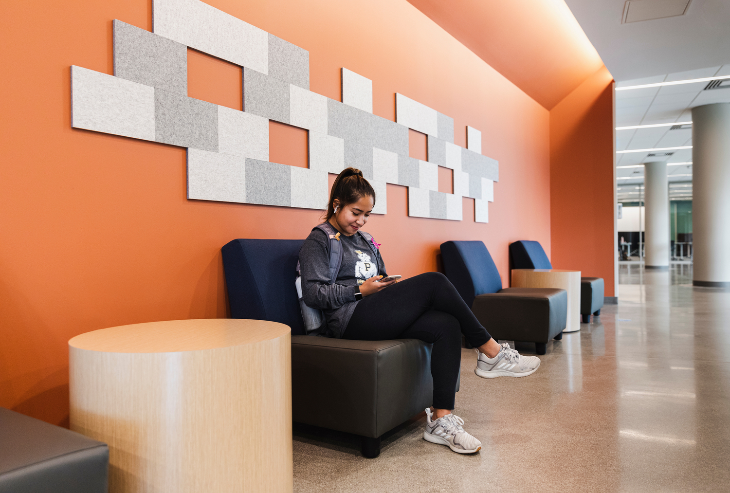 Student sitting in a hallway painted orange