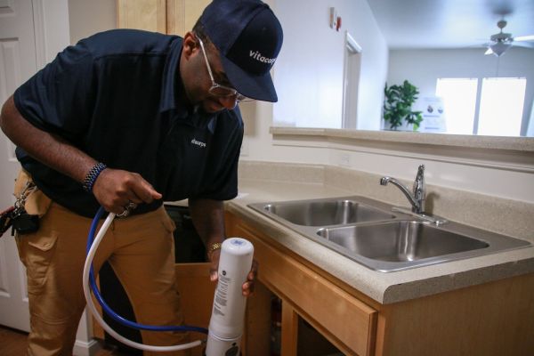 A Vitacorps tech installs a water filtration system.