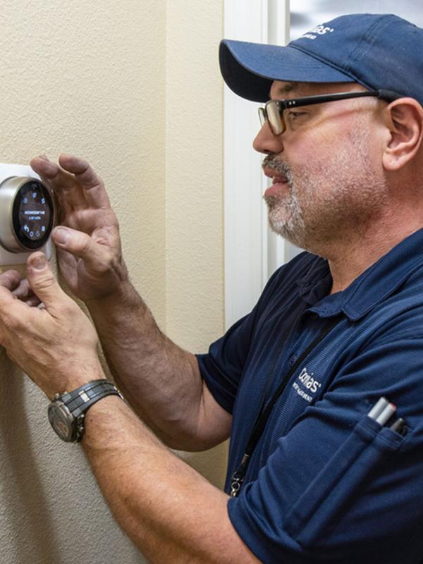 Corvias maintenance technician adjusts thermostat in military home