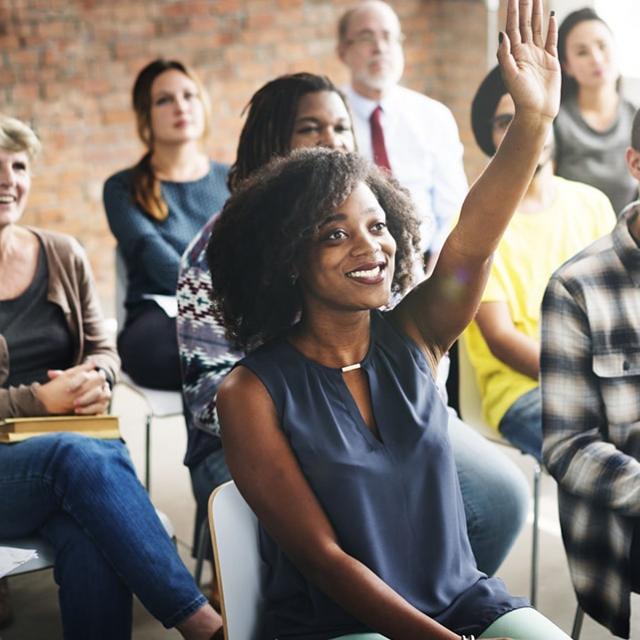 A group of people with a woman raising her hand