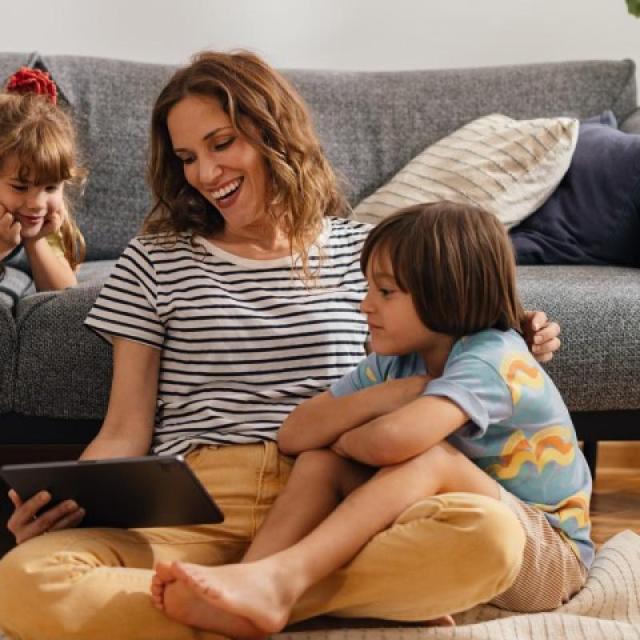 Mom sitting on the living room floor with her kids, smiling