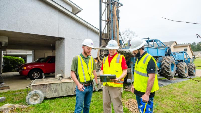 Three men in construction gear looking at paperwork