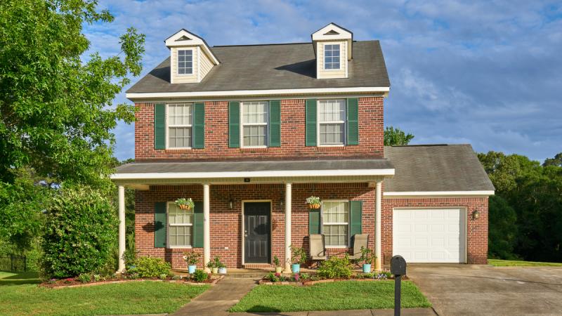Outside of a brick house with a garage and driveway