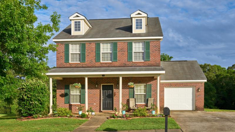 Outside of a brick house with a garage and driveway