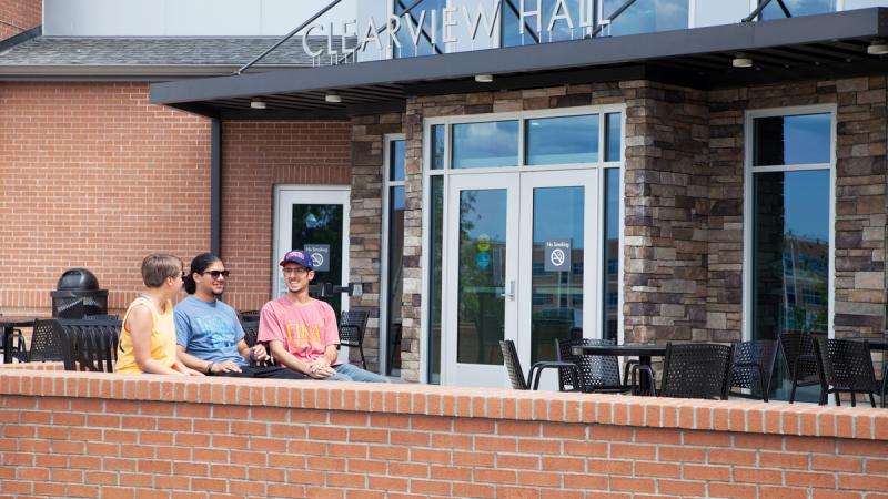 Students sitting on a patio outside of a building