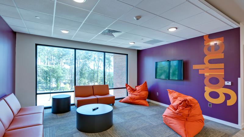 Room with a purple wall and couches and beanbag chairs