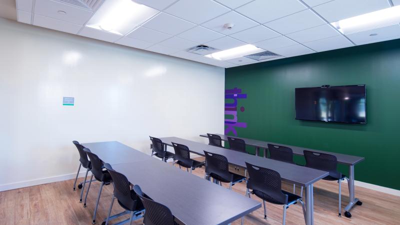 Room with long tables and chairs and a TV