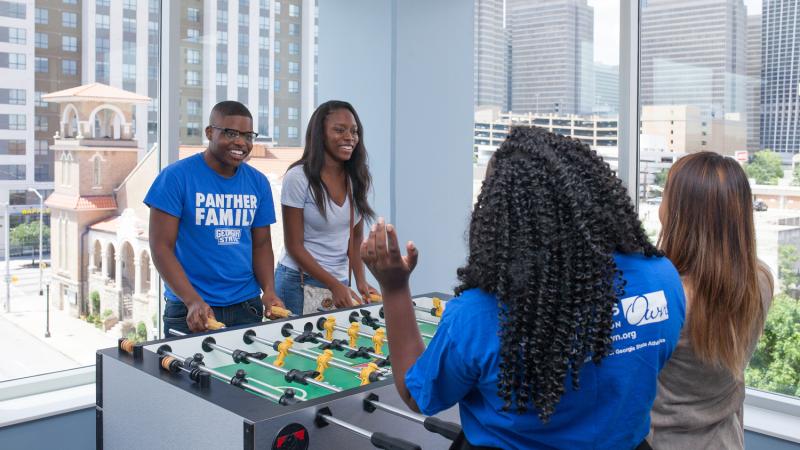 4 students playing foosball 