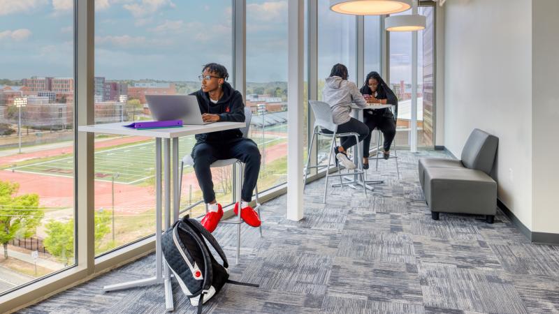 Students studying next to tall glass windows