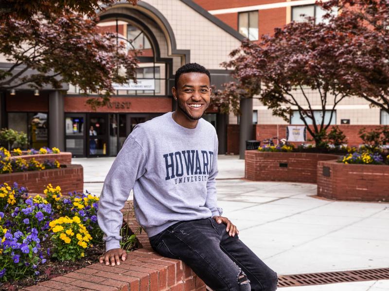Student sitting outside a building wearing a Howard University pullover