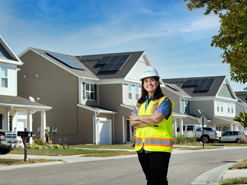 Woman in construction gear standing in front of a row of homes