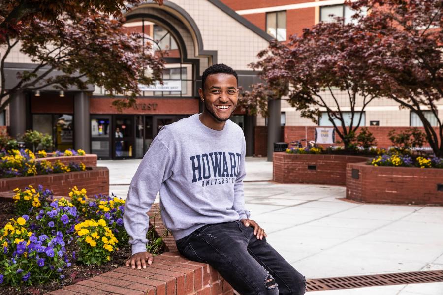Student sitting outside a building wearing a Howard University pullover