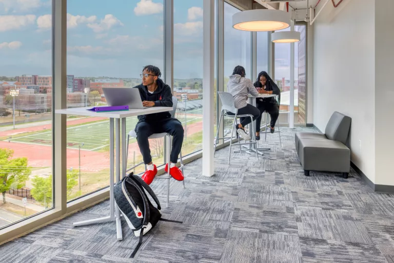 Students studying next to tall glass windows